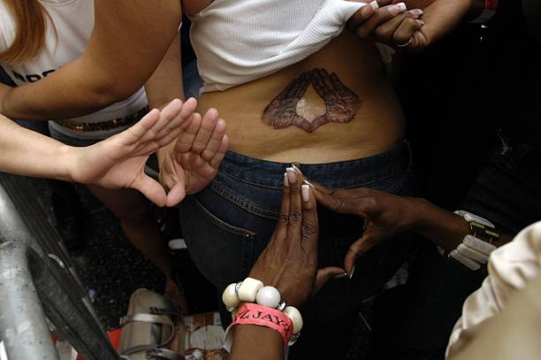 HOLLYWOOD - NOVEMBER 22:  A woman shows off her brand-new tattoo of Jay-Z's trademark hand signal while waiting in line with fans to have him sign their copies of his new album "Kingdom Come" at the Virgin Megastore on November 22, 2006 in Hollywood, California.  (Photo by Amanda Edwards/Getty Images)