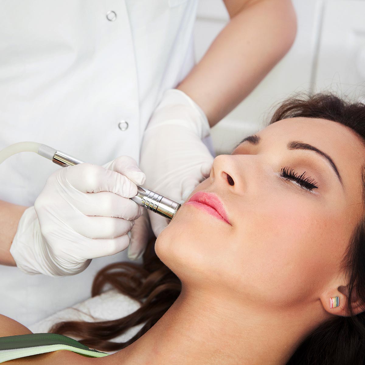 Woman getting laser face treatment in medical spa center